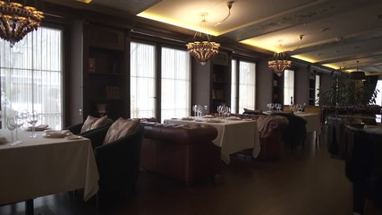 Beautiful and richly served tables in the restaurant. A cozy decorated room with leather sofas and comfortabe armchairs. Stylish glasses, plates with napkins and silver cutlery on the tables
