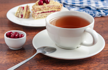 cup of tea sweet cake  cherry berries in bowl on wooden table soft focus