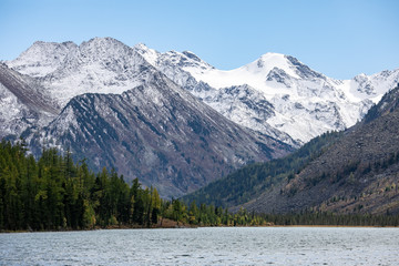 landscape with mountains, green trees and blue lake on a cloudy sky background Altai