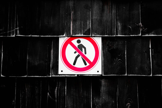 Prohibition No Pedestrian Sign next the fence. Prohibited signs figura of walking man in a crossed circle on black background