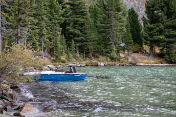 Mountain lake in spruce forest on a background a blue boat