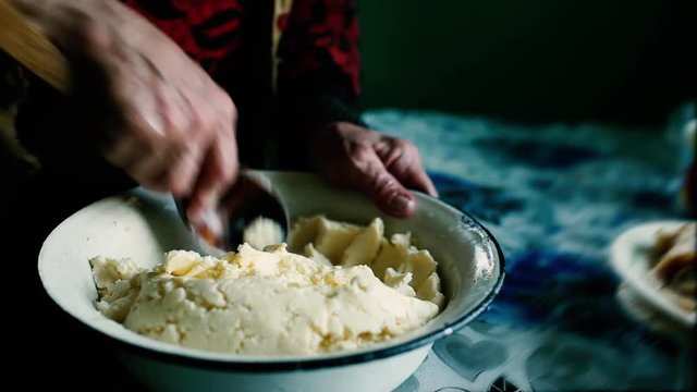 hands of an old woman with a wooden spoon, whip homemade butter with whey