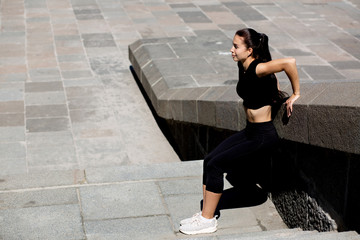 Awesome fitness girl wearing sport apparel stretching at the city. Space for text