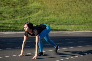 Fototapeta na wymiar Sporty brunette girl running on the daylight on the jogging track. Empty space