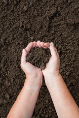 human hands with soil on brown soil background