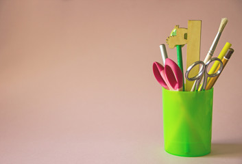 Stationery. Writing accessories pen, pencil, scissors, ruler in a glass on a pink background. Back to school. Office supplies products, Copy space