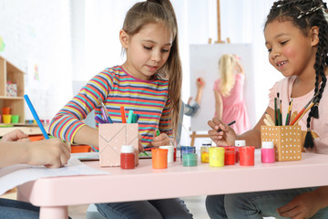 Cute little children drawing at painting lesson indoors