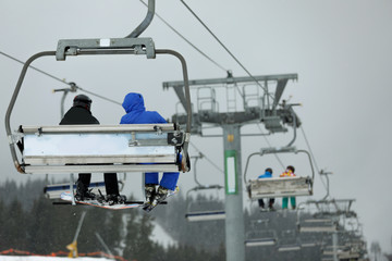 Chairlift with people at ski resort. Winter vacation