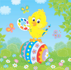 Little yellow chick coloring an Easter egg among flowers on green grass of a lawn on a sunny spring day, vector illustration in a cartoon style