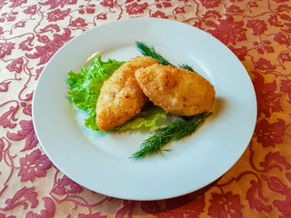 Pozharsky cutlets cooked according to an old Russian recipe on a white plate with greens