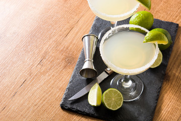 Margarita cocktails with lime in glass on wooden table. Copyspace