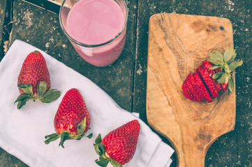  Strawberry smoothie with strawberries around on a rustic wooden table in the countryside