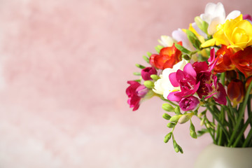 Bouquet of beautiful spring freesia flowers in vase on color background, space for text