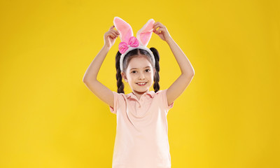 Portrait of little girl in Easter bunny ears headband on color background