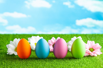 Easter eggs and flowers on the grass and blue sky background