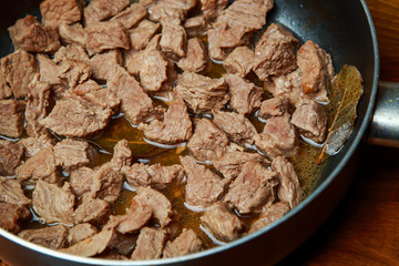 veal meat stew in a skillet with vegetables in sour cream sauce