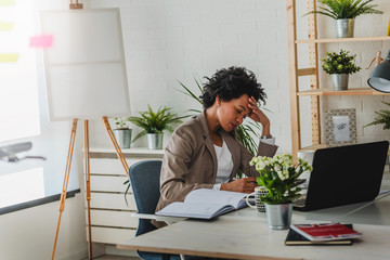 Serious african-american business woman working on laptop at office