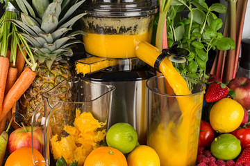 slow juicer in kitchen with many fruit and vegetable orange vitamin juice healthy lifestyle concept...