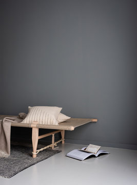 Tagesbett in nordischen Design vor grauer Wand als gemürliche Leseecke