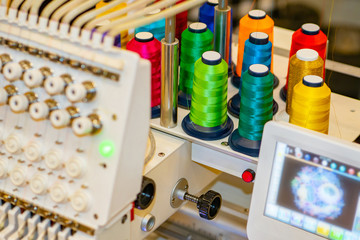 Spools of thread on the embroidery machine. Computer embroidery machine. Industrial embroidery equipment. Programmable embroidery machine. Embroidery patterns.