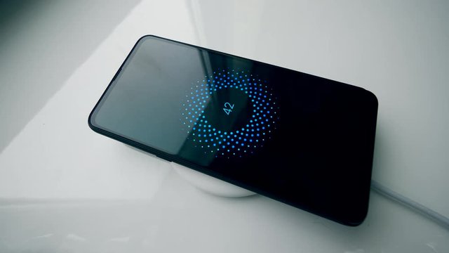 Automated induction charger charginga smartphone on a table.