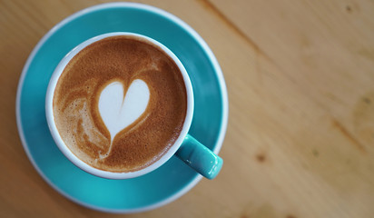 cappuccino on light blue cup upon wooden table