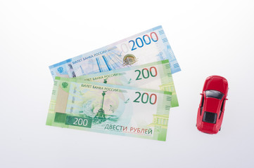 ruble banknotes and red toy car, Russian currency on a white background. concept of shopping or...