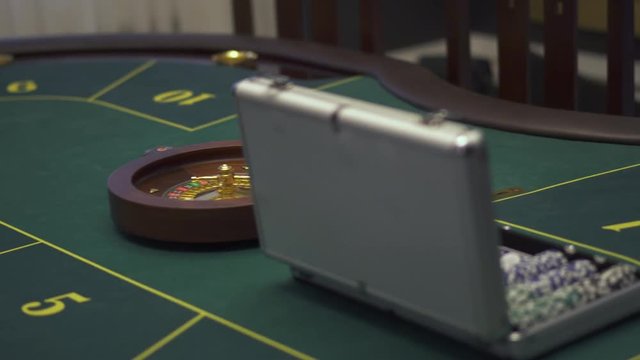 Close up view of the gaming table with green surface with poker set on it in modern casino. Comfortable place with luxury interior waiting for the guests