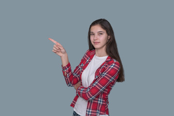 young girl points with forefinger, gray wall background