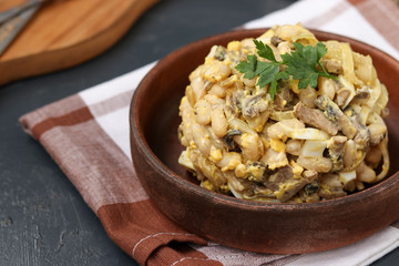 Salad with beans, parsley and champignons in a brown bowl over a dark background
