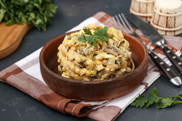 Salad with beans, parsley and champignons in a brown bowl over a dark background