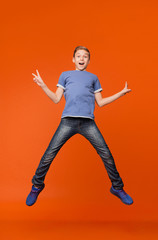 Happy joyful boy jumping up in air, demonstrating v-signs