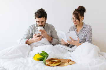 Young couple in bed having breakfast