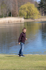 Fototapeta na wymiar The boyl is walking along the shore of the lake in the spring.