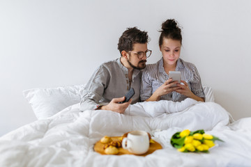 Couple in bed looking at mobile phone