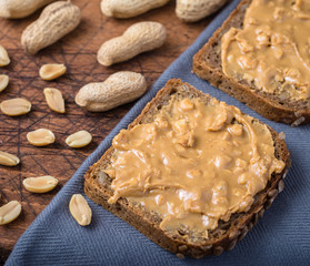 Fototapeta na wymiar Bread spread with peanut butter on grey napkin.