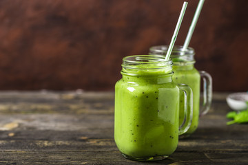 Green smoothie made by avocado, lemon and kiwi on natural wooden background.