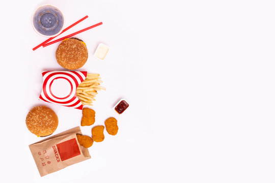 Flat lay of Delicious fresh burger, french fries, chicket nagets and cola glass on white background. Fastfood concept dinner