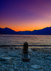 A traveller enjoying violet sunset in the port of Ascona, Switzerland