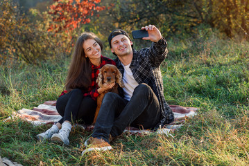Stylish modern couple have a video call with their friends sitting in the nature. Young happy...