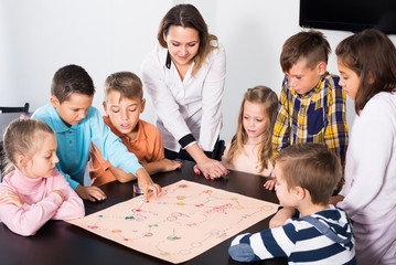 Elementary age glad children at table with board game and dice