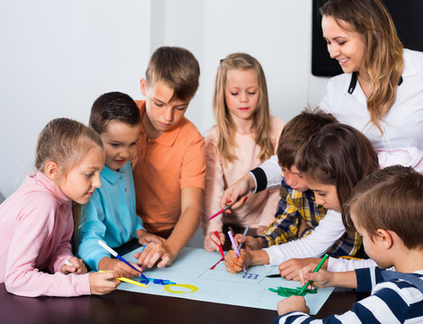 Children with teacher drawing together in classroom