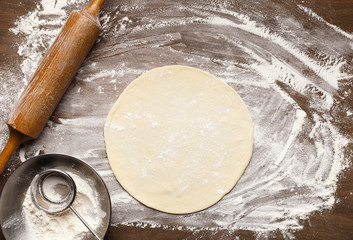 Raw pizza base. Rolled out dough on floured surface
