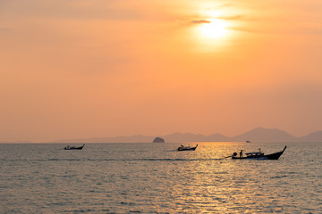 Local thai longtail motor boats under golden sun in the sea water at orange sunset in Ao Nang in Krabi goes to the Boat station in Nopparat Thara