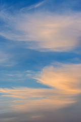 Feathery blurred clouds at sunset on blue sky background