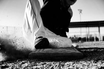Baseball player sliding into base closeup.  Sports action image in black and white.