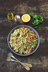 Arabic salad tabbouleh in a bowl. Middle Eastern cuisine. Healthy salad with bulgur, parsley and vegetables. Vegan salad with bulgur. Tabouli salad