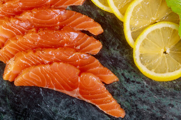 Salmon slices with herbs on marble plate background