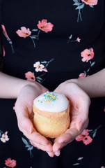 Little Easter cake with white fudge glazing and confectionery sprinkles in female hands