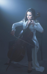 Fototapeta na wymiar Beautiful woman in a white coat plays the cello